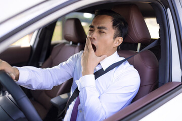 Business man looks tired yawning while driving the car - obrazy, fototapety, plakaty