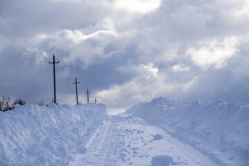 A deserted country road through snow-covered fields. Poor visibility due to a snowstorm.