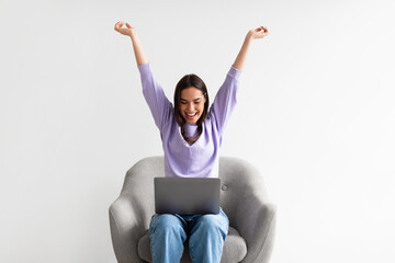 Excited lady with laptop raising her arms up, winning online casino bet, shopping on huge discount, achieving success