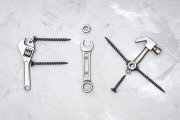 Word FIX made from hand tools and fasteners on gray