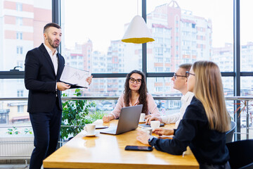 Successful meeting of business people, discussing new business ideas, using diagrams, sitting together. Modern office background. Meeting of business partners at the conference on business development