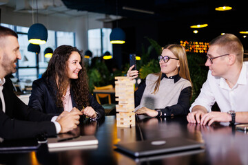 Businessmen are playing Jenga games. They sit in the office and play games. Concept photo for design and work.