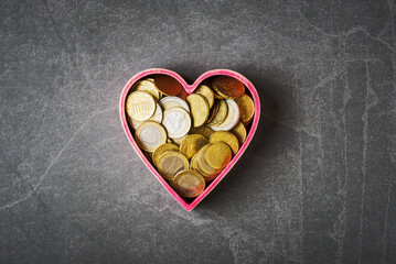 Euro currency coins in heart shaped box on grey stone background. Love and money concept