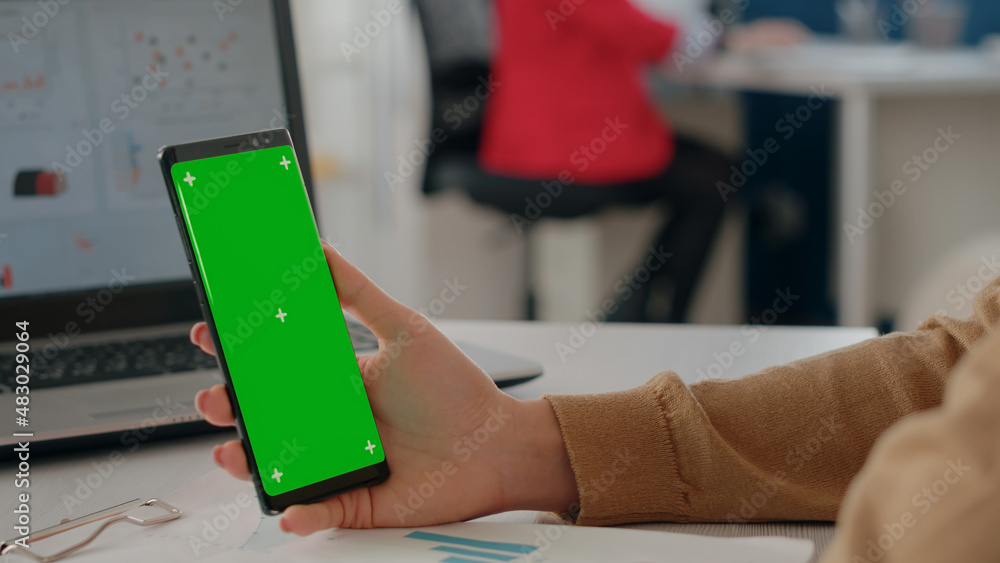 Poster close up of hand holding green screen vertically on mobile phone. person working with mock up blank 