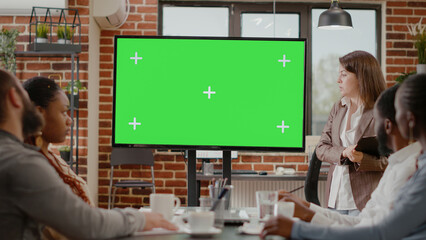 Diverse business people looking at green screen on monitor display, doing presentation with chroma...
