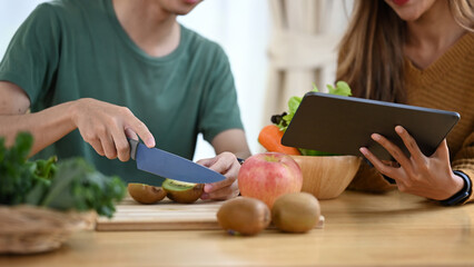 Young couple preparing ingredients for making healthy vegan salad with fresh vegetables in the...