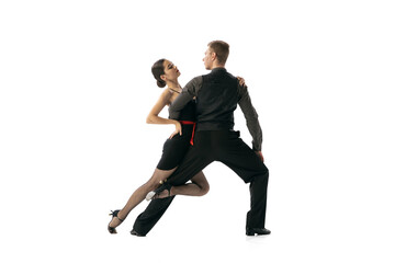 Beautiful sportive young man and woman dancing Argentine tango isolated on white studio background. Artists in black stage costumes