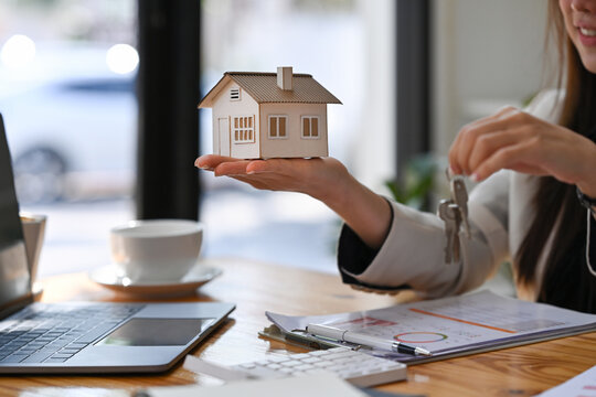Estate agent holding house model and house key in hand. Mortgage Real estate investment and insurance concept.
