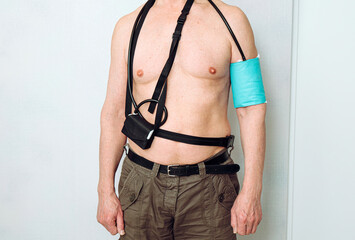 Body of a middle aged man using portable Ambulatory Blood Pressure Monitor (ABPM) for taking...