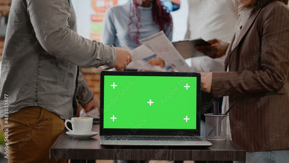 Poster workmates with papers using green screen on laptop in startup office, using isolated mock up templat