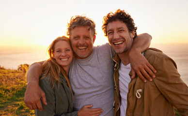 Evening adventuring with dad. Portrait of a father with his son and daughter on a grassy hill at...