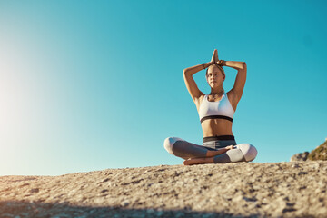 Fototapeta na wymiar I do yoga, do you. Shot of a young woman doing yoga at the beach.