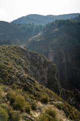 Obraz premium Paisaje de la sierra de Granada con tonos verdes y cielo despejado con nubes bajas agregando neblina a la escena 
