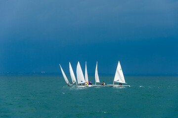 Small sailing boats in the sea in cloudy summer day, training of sailing school