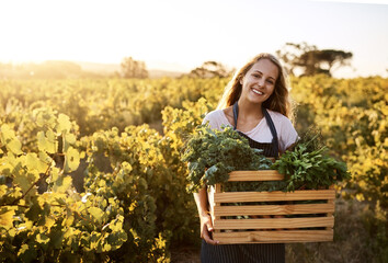 Stock your pantry with fresh produce. Shot of a young woman holding a crate full of freshly picked produce on a farm.