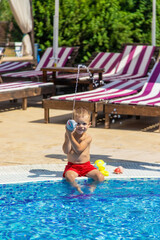 Naklejka premium the child sits near the pool is played with a water pistol