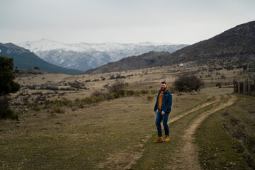 Obraz premium Chico con barba y alto en camino de tierra con sierra nevada de fondo