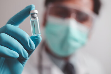 doctor or scientist in the COVID-19 medical vaccine research and development laboratory holds a syringe with a liquid vaccine to study and analyze antibody samples for the patient.
