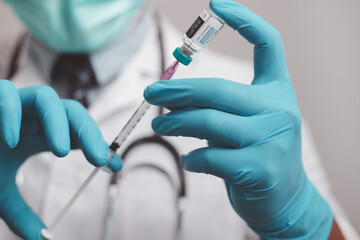 doctor or scientist in the COVID-19 medical vaccine research and development laboratory holds a syringe with a liquid vaccine to study and analyze antibody samples for the patient.
