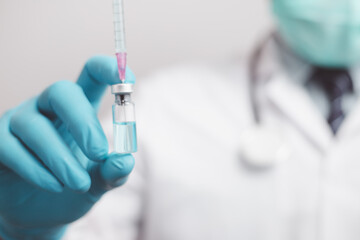 doctor or scientist in the COVID-19 medical vaccine research and development laboratory holds a syringe with a liquid vaccine to study and analyze antibody samples for the patient.
