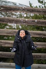 Chica joven guapa en la nieve posando feliz ante la cámara y poniendo caras graciosas
