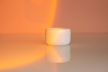 White jar with a cosmic day, night cream on a beige background in the light of the setting sun. Stylish look of the product, mock up, without a brand.