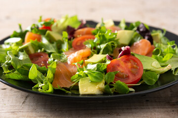 Salmon and avocado salad in plate on wooden table	