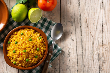 Traditional Mexican rice served with green peas in bowl on wooden table. Top view. Copy space