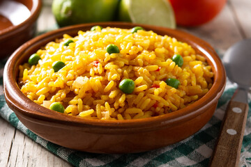Traditional Mexican rice served with green peas in bowl on wooden table	