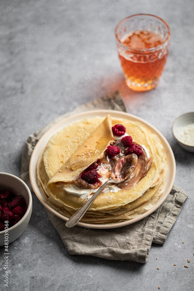 Wall mural assiette de crêpes à la crème de marron, yaourt et framboises avec verre de cidre sur une table