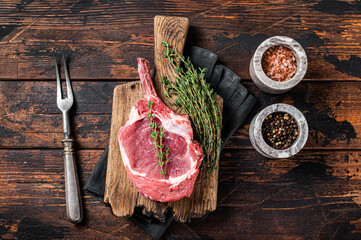 Uncooked Raw Rib eye or Tomahawk beef (veal) steak on butcher cutting board. Wooden background. Top...