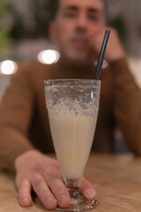 A vertical shot of a middle age man having a drink inside a charming cafe. Having drinks with a friend in a spectacular place. Enjoying a freshly smoothie.