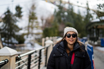 Chica guapa andando por estación de esquí con la nieve de fondo en la montaña