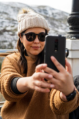 Chica joven guapa con gafas de sol en una terraza sonriendo y bebiendo refresco