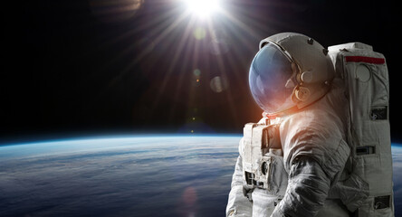 Astronaut in space. Spaceman on black background near Earth planet surface. Sci-fi wallpaper....