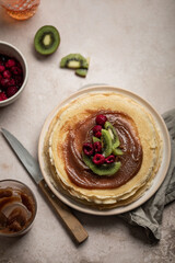 Assiette de crêpes à la crème de marron, kiwi et framboises avec verre de cidre sur une table	