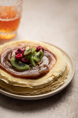 Assiette de crêpes à la crème de marron, kiwi et framboises avec verre de cidre sur une table	