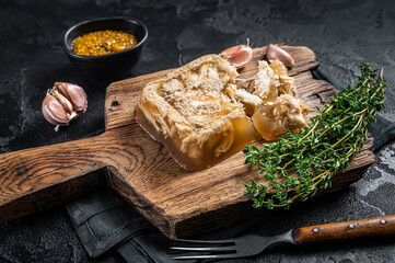 Aspic with chicken meat on wooden board. Black background. Top view
