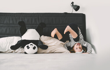 Happy little girl playing with soft big plush panda at home. Concept of family, healthy sleep of...