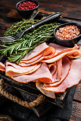 Italian Prosciutto cotto Ham slices in wooden tray with thyme and rosemary. Wooden background. Top...