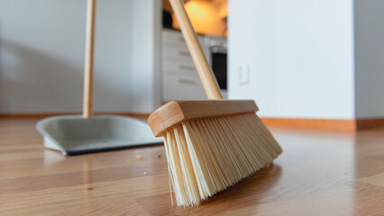 Closeup of the stylish wooden brush sweeping litter into the metal shovel.