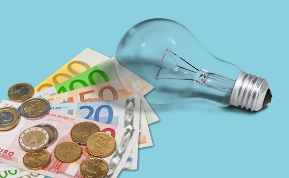 Light bulb and money banknotes. Increasing of electricity costs for residential and business users