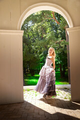 Portrait of beautiful pretty bride in an unusual wedding dress walking and standing alone in the green park in a summer or spring day