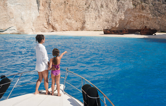 Young mother with daughter enjoying beautiful Navagio beach from yacht