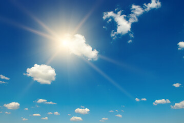Naklejka na ściany i meble Blue sky with white fluffy clouds and bright sun
