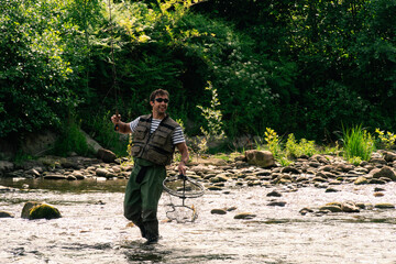 Young man fishing trouts in the river