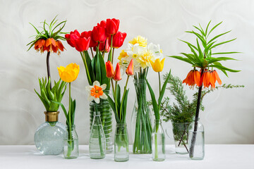 Different spring flowers in transparent vases on the table. Flower shop