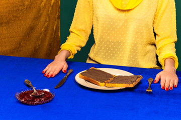 Food pop art photography. Cropped portrait of girl and sweet chocolate toasts on blue tablecloth. Vintage, retro style interior