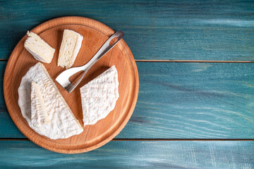 Slices of cheese camembert or brie on wooden board. Delicious breakfast or snack, Clean eating, dieting, vegan food concept. top view. Milk production. Space for text