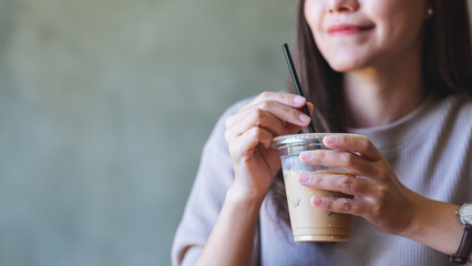 Naklejka premium Closeup of a young woman holding and drinking iced coffee